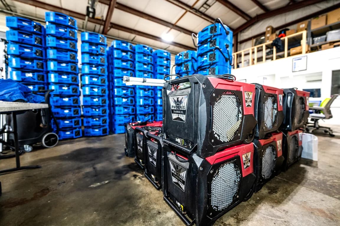Red dehumidifiers and stacked blue air movers in a warehouse