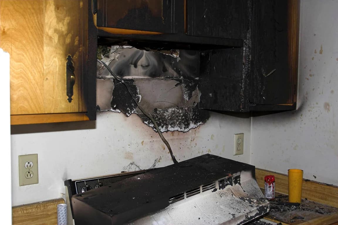 Black soot on kitchen cabinets and the wall around a range after a fire