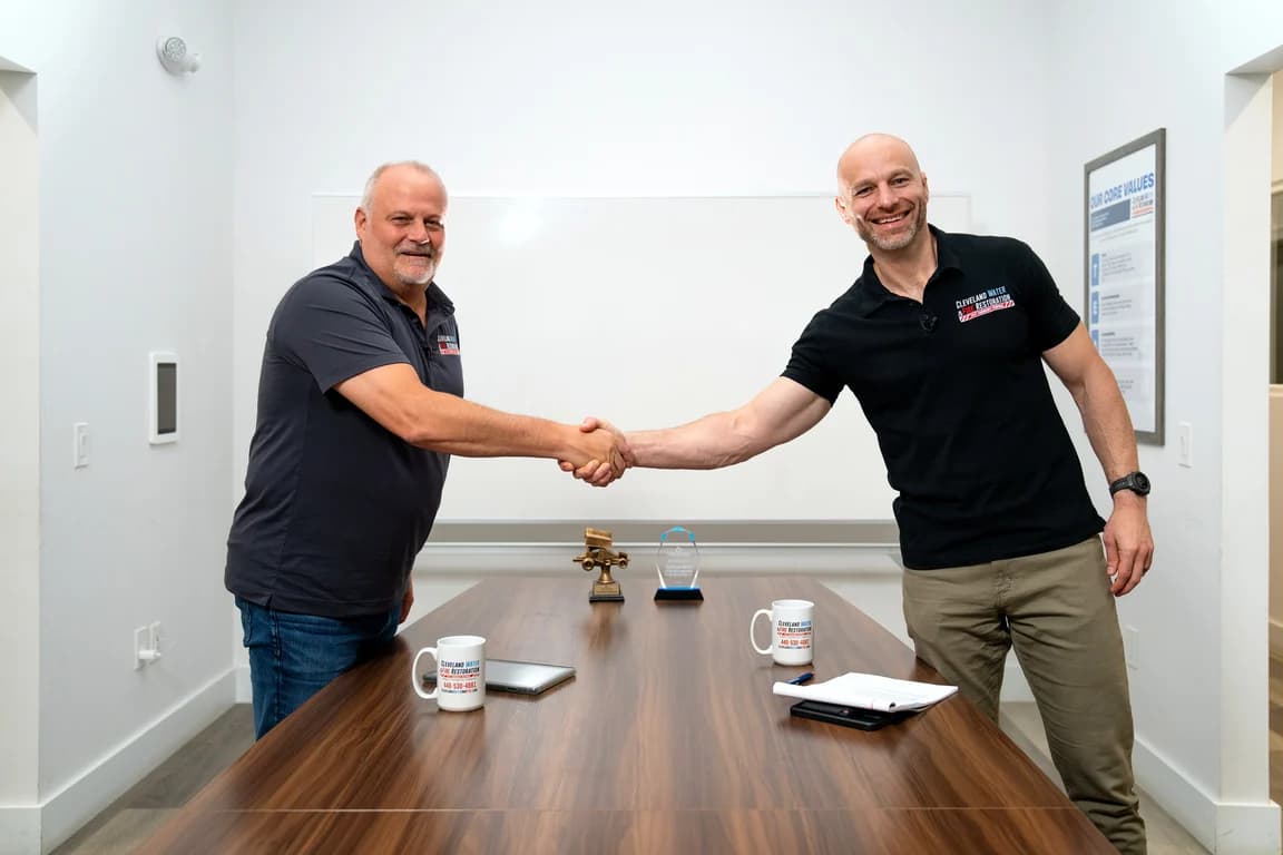 Two Cleveland Water and Fire Restoration, Inc. owners shaking hands across a conference table
