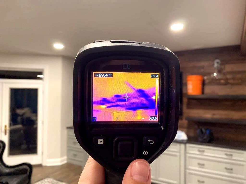 Handheld thermal camera displaying a ceiling temperature pattern
