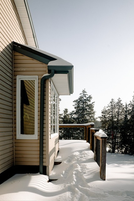 A suburban home with wooden porch covered in snow. 
